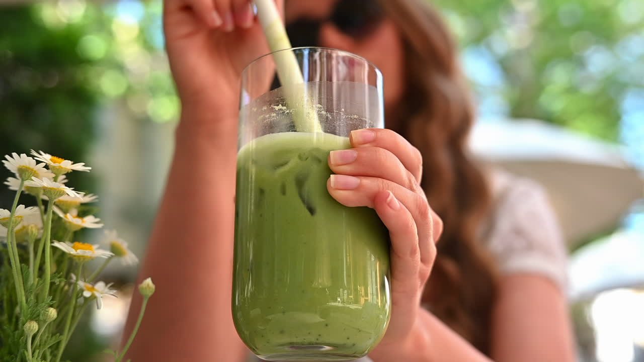 Donna che beve tè matcha freddo in un terrazzo di un ristorante