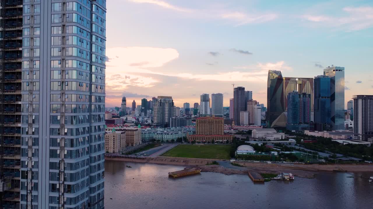 Drone subindo perto de arquitetura de arranha-céus ao longo do Rio Tonle Bassac, paisagem urbana ao anoitecer em Koh Pich, Phnom Penh.