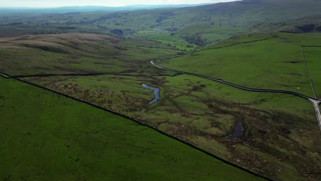 Backward-tilt-up-reveal-of-small-lake-in-the-middle-of-north-yorkshire-countryside-revealing-the-miles-and-hills-and-mountains-surrounding-the-water-in-this-remote-location-on-a-sunny-weather-day