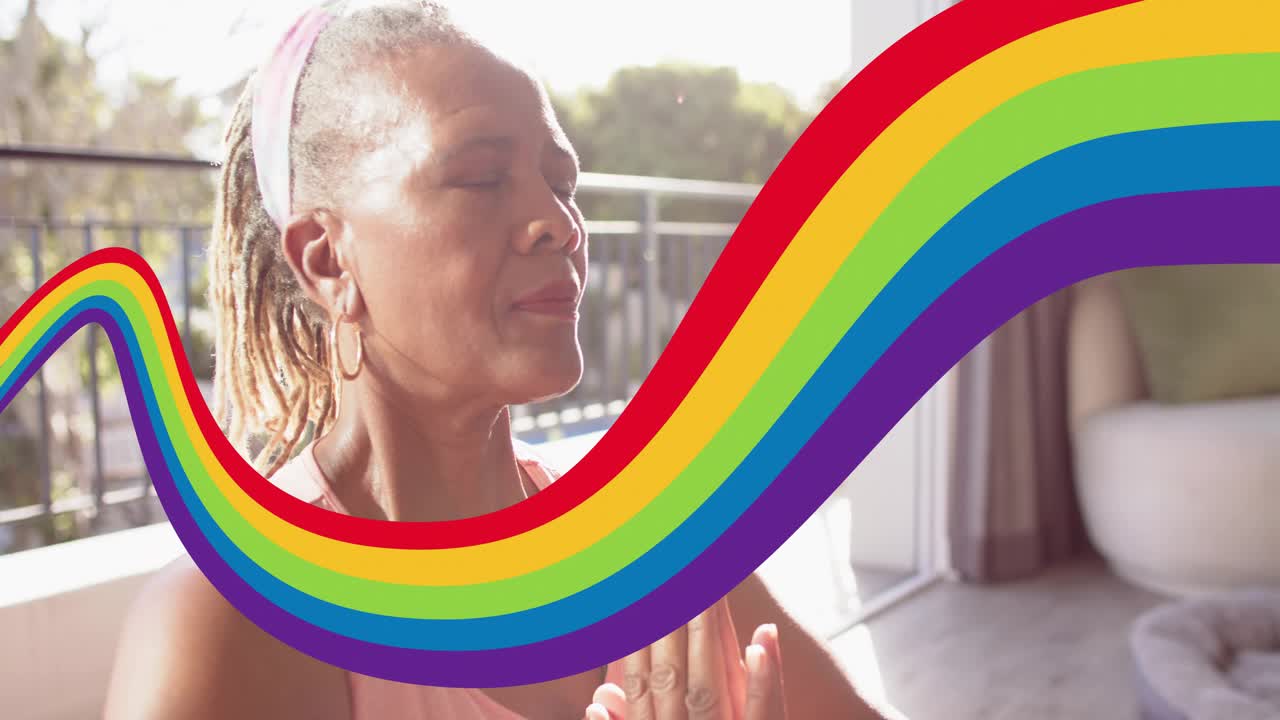 Senior woman meditating for health on balcony, palms together, rainbow sweeping causing eye closing