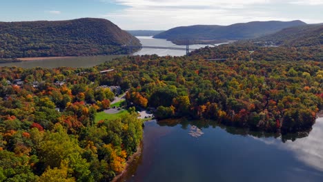 an aerial view of a reflective lake with colorful trees in upstate ny