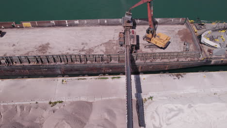 top view of heavy machine pouring out sand at the kingsville marina from gravel ship