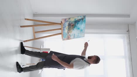 a talented artist using a brush creates a modern masterpiece of oil painting - a talented artist, using a brush, creates a modern masterpiece of oil painting. creative studio with canvas of bright colors. close-up. high quality full footage