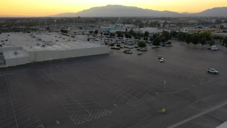 torre celular disfrazada de palmera en un gran estacionamiento comercial y un atardecer de montaña en el fondo