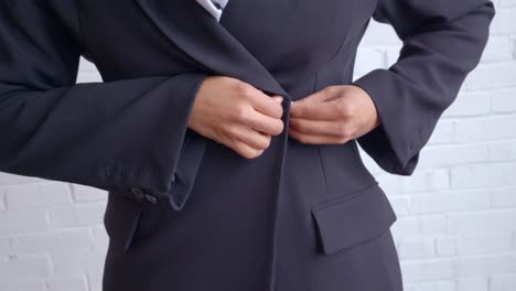 a woman in a black trench coat and white scarf buttoning her coat, set against a clean white background.
