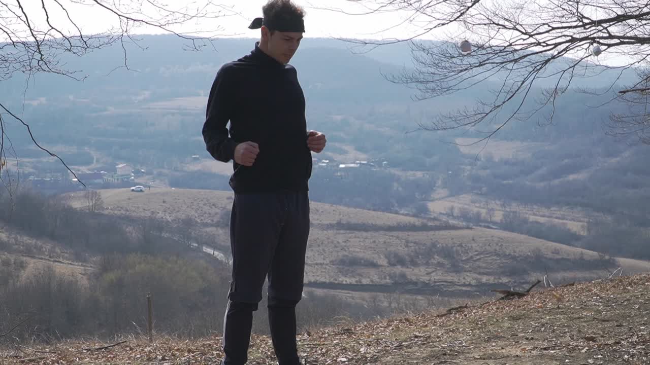 A man warms up on a hilltop with a panoramic view of a peaceful valley. Ideal for themes of nature, wellness, solitude, and mindful living