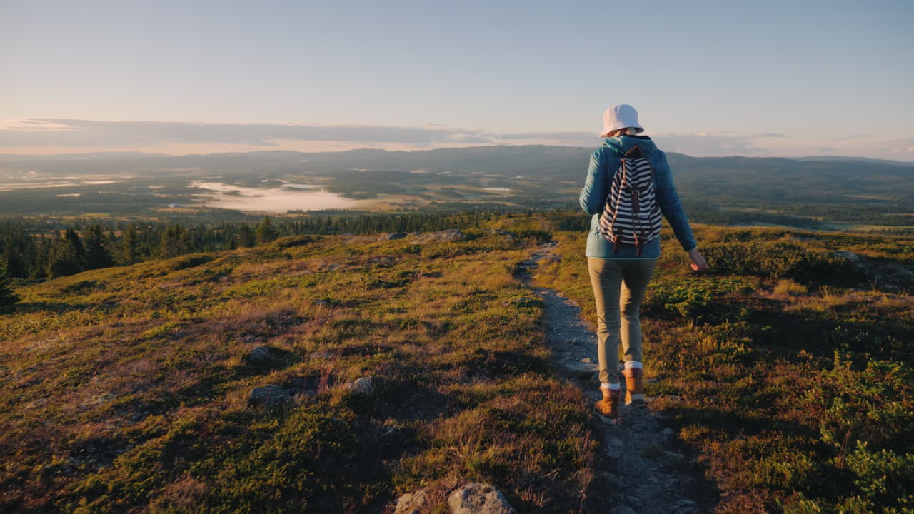 una mujer viajera con una mochila a la espalda camina por las pintorescas tierras altas de noruega j