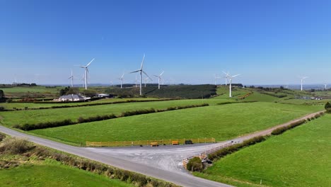 wind turbines, cornasaus, county cavan, ireland, april 2023. drone pushes forward over green farmland with windmills spinning on clear day under a clear blue sky.
