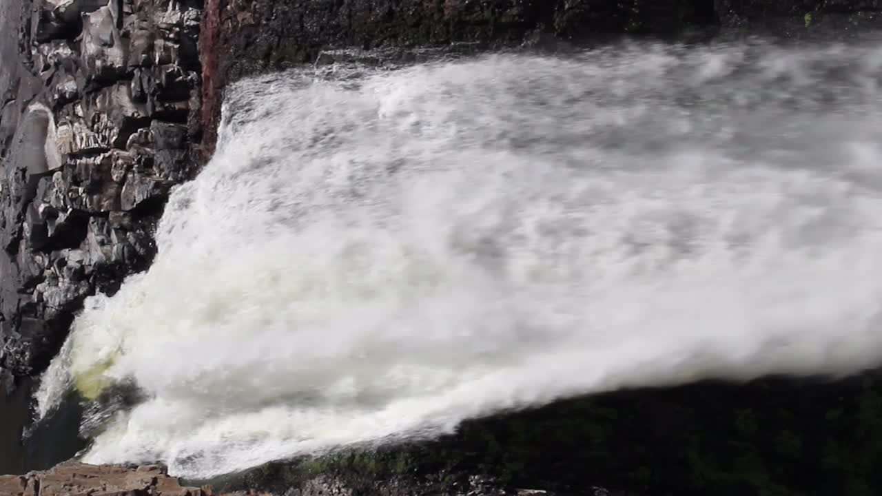 Vertical format: Water rushes through top of Palouse Falls waterfall