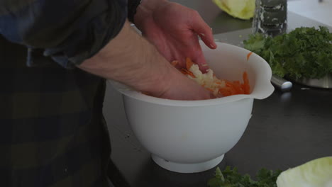 fermented vegetables, sauerkraut or kimchi being prepared by hand in a bowl, close up