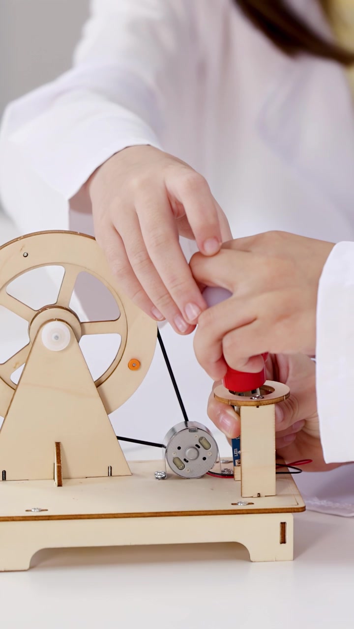 Close-up of children in lab coats building an electricity kit for STEM education.