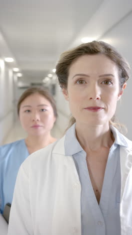 vertical video portrait of diverse female doctors in hospital corridor, slow motion