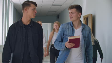 Two-students-walk-down-the-hall-of-the-University-and-talk-and-discuss.