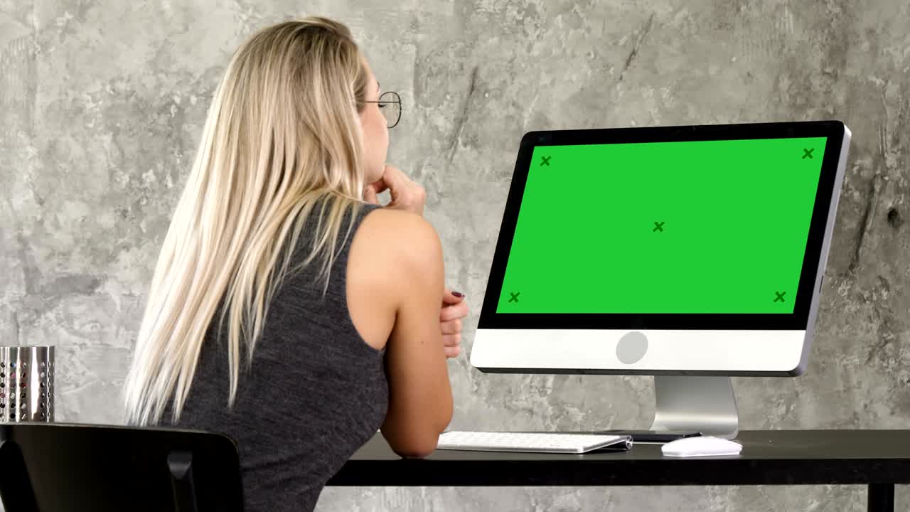 Woman freelancer looking at computer monitor. Green Screen Mock-up Display