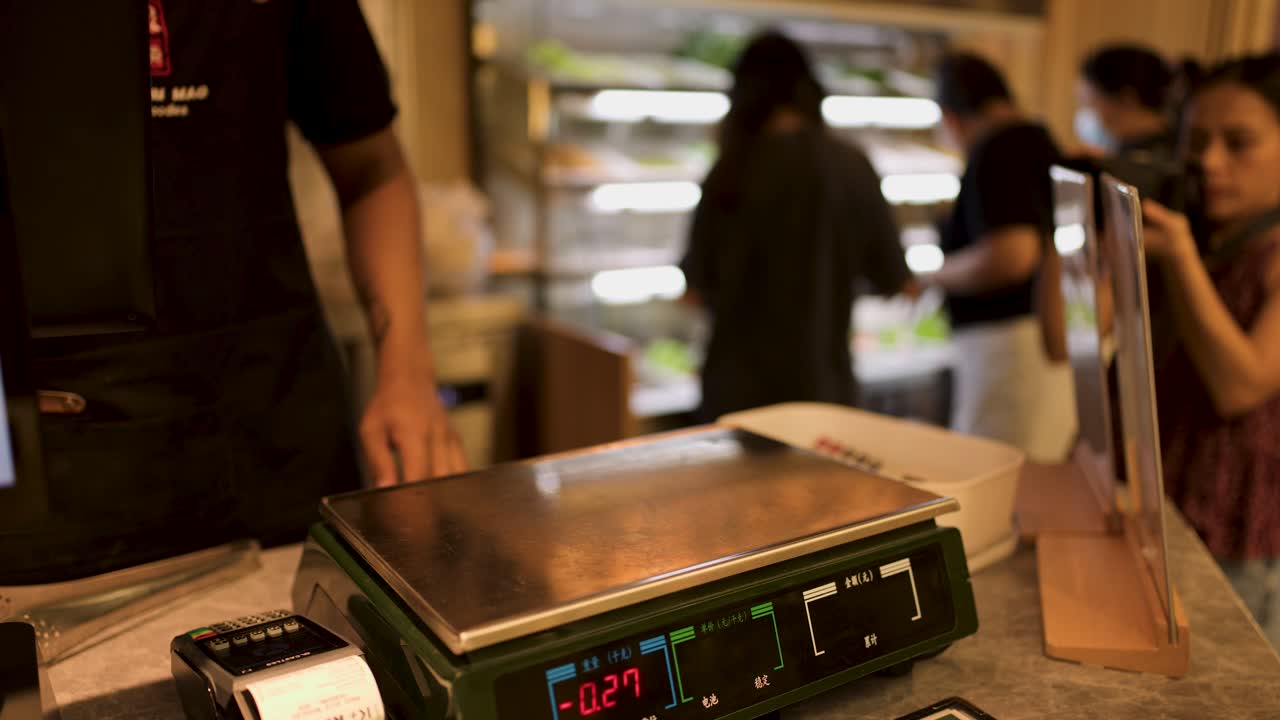Restaurant staff weigh fresh hotpot vegetables and ingredients in plastic bowl on digital scale