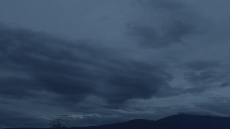 Bewölkter-Himmel,-Der-Sich-Langsam-In-Der-Abenddämmerung-Zwischen-Bergen-Bewegt