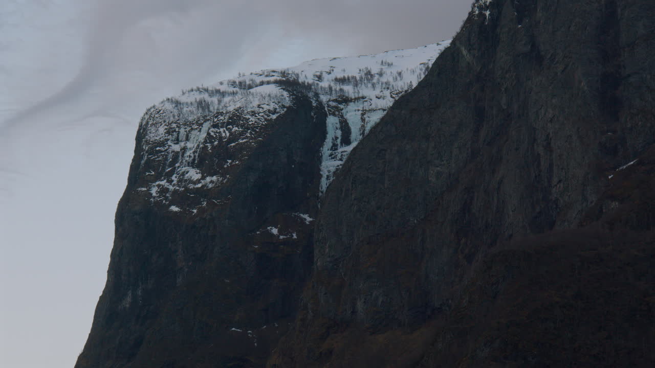 Wide shot slow pan of the snowy Mountain tops and side in the Sogneflord on way to Flam