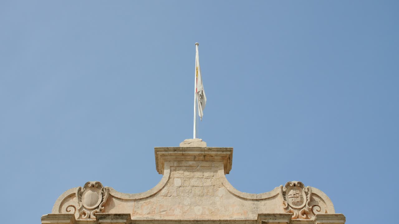 맑고 푸른 하늘을 배경으로 몰타의 성문 위에 흔들리는 엠디나의 국기