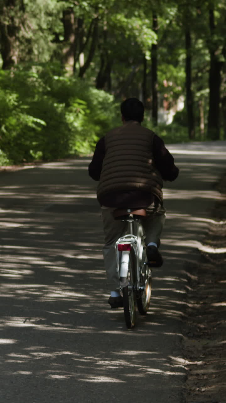 Person Cycling on Road in Forest