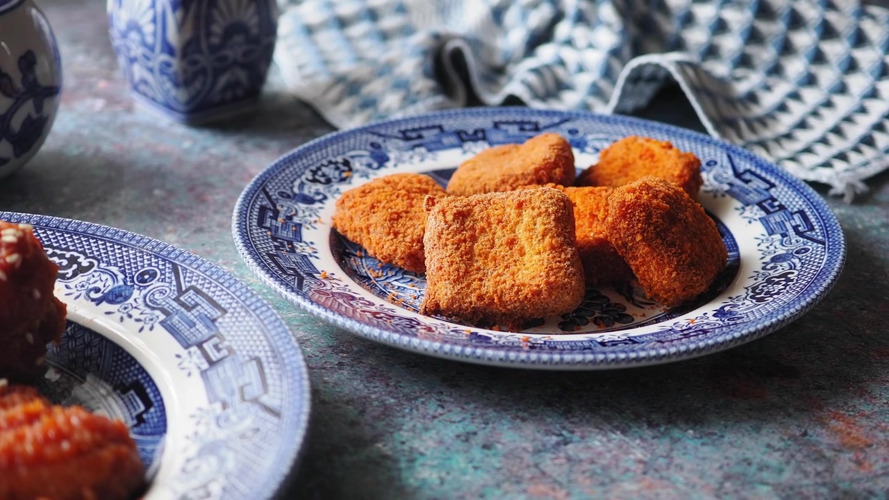 Bocconcini di pollo fritti croccanti serviti su un piatto decorativo blu e bianco