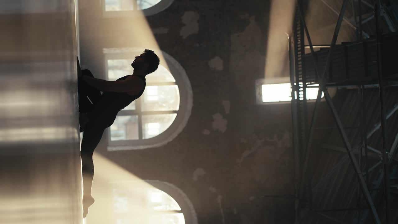 검은색 스포츠 여름 유니폼을 입은 남성 운동 선수의 수직 비디오 실루 ⁇ 이 근육을  ⁇ 는 운동을 하고 있습니다.