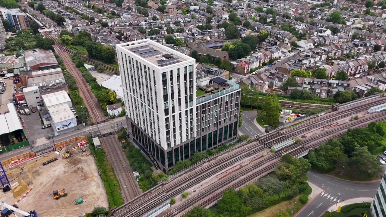 Una nuova torre per uffici bianca si erge accanto alla ferrovia e a un cantiere con una gru blu in un quartiere in riqualificazione