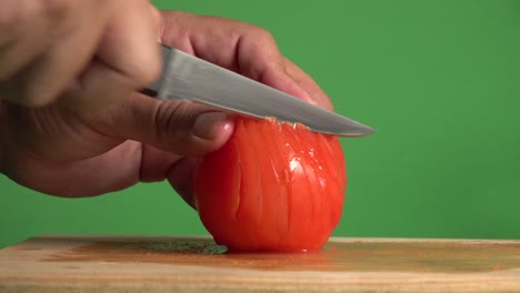 hands cutting a red tomato on a chroma background