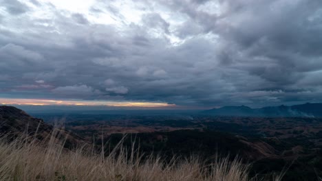 sunset on viti levu island with dramatic dark clouds in sky, grass swaying in breeze, timelapse