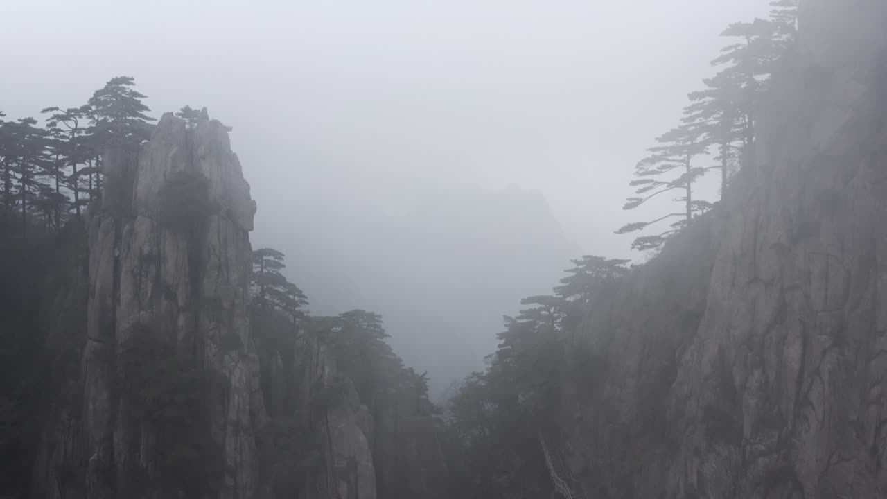 Huangshan valley, aerial pull-back reveal through mountain peaks in cloud