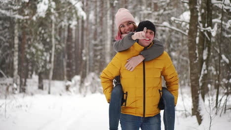 happy loving couple walking in snowy winter forest, spending christmas vacation together. outdoor seasonal activities. lifestyle capture.