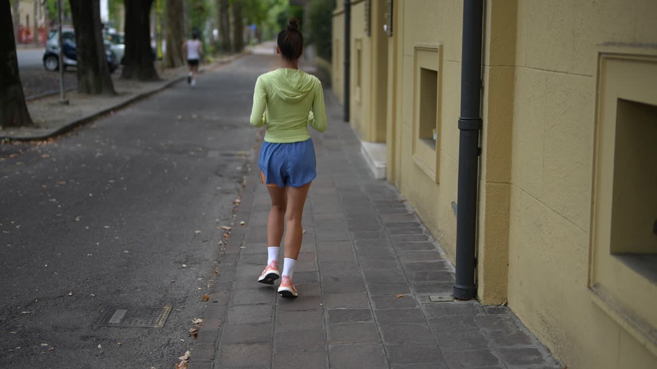 mujer corriendo por la acera de la ciudad