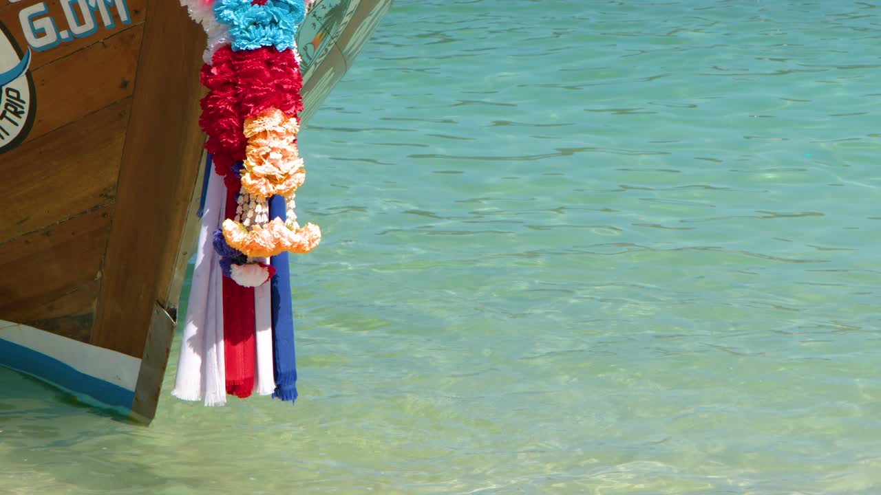 Un'ancora di metallo viene sollevata da acqua tropicale limpida su una barca di legno decorata
