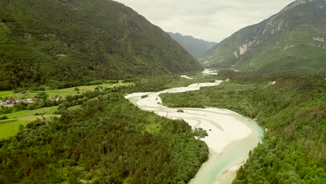 aerial view of soca river surrounded by a small town and many hills in slovenia.