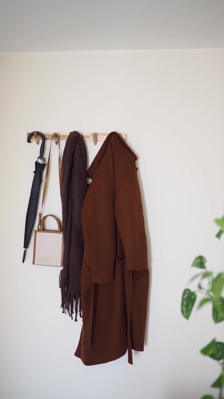 Cappotto marrone e accessori appesi a un gancio a muro