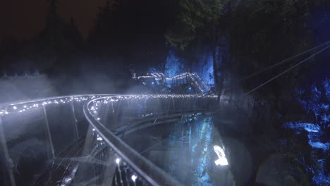 plataforma circular elevada en el cañón decorada con luces navideñas azules, noche lluviosa