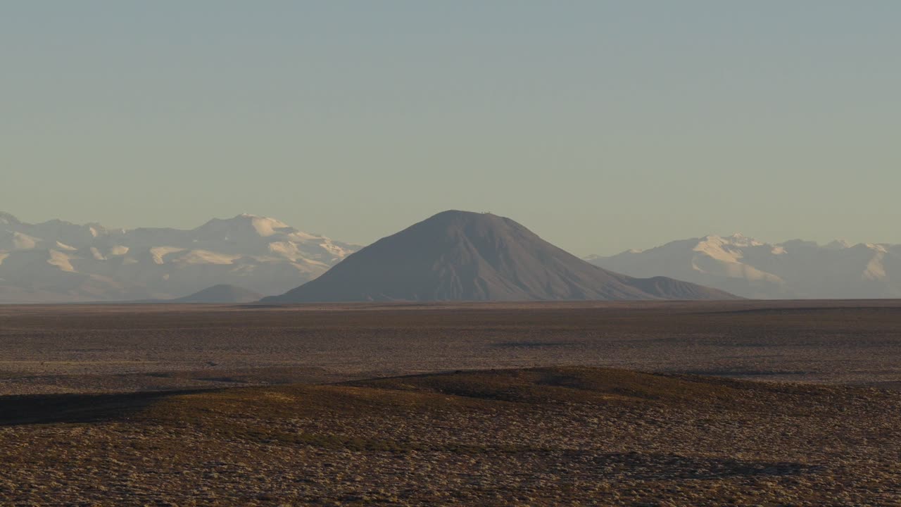 Cinematic still frame captures Diamante volcano shrouded in morning haze, seamlessly merging with the Andes. Ideal for documentaries or nature intros.