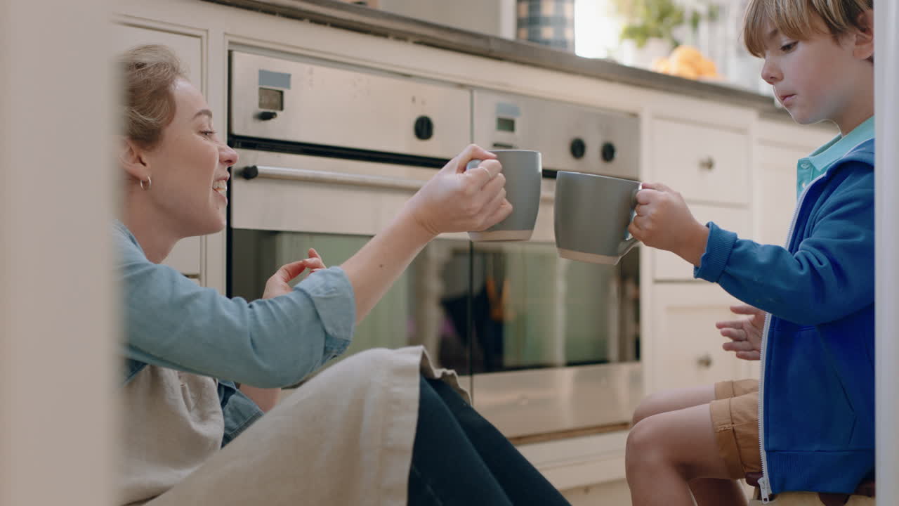 엄마와 아들이 뜨거운 초콜릿을 마시고 부 ⁇ 에서 토스트를 만들고 행복한 엄마가 작은 아들을 돌보고 집에서 맛있는 음료를 즐기고 있습니다.