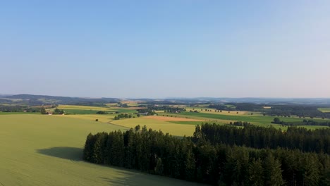 Zeitraffer,-Bei-Dem-Die-Kamera-Zu-Boden-Sinkt-Und-Im-Hintergrund-Wälder,-Felder-Und-Wiesen-Zu-Sehen-Sind