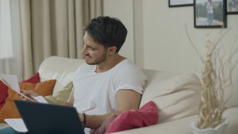 hombre de negocios buscando documentos de datos financieros en el sofá de casa. hombre de negocios feliz