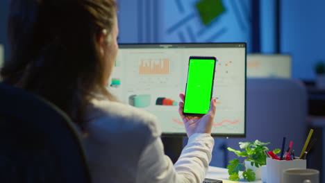 Businesswoman-looking-at-green-screen-monitor-of-smartphone