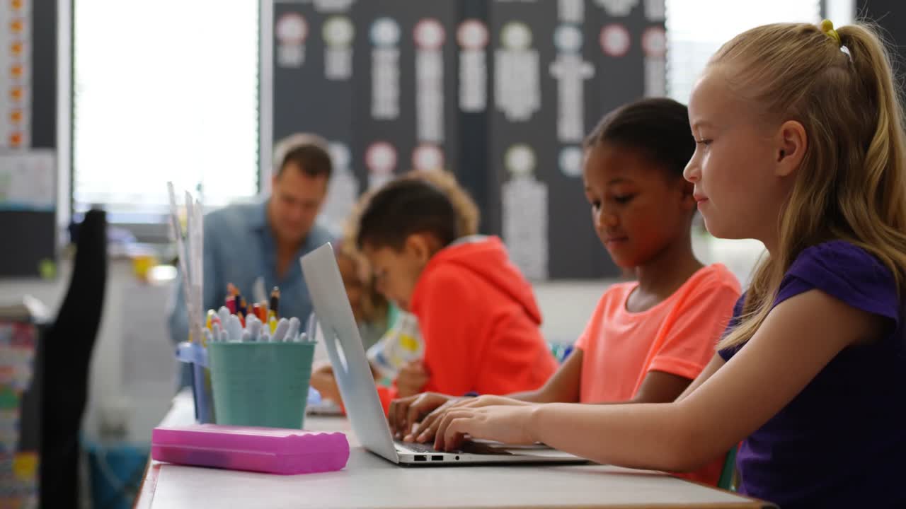 Side view of Mixed-race schoolgirls studying on laptop in the classroom 4k