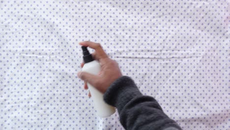 a person spraying a white fabric with a spray bottle