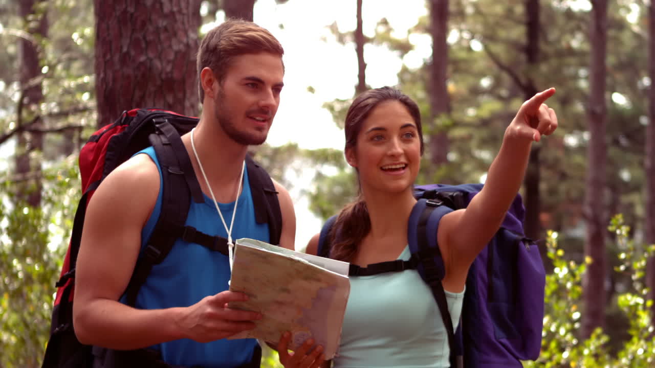 una pareja caminando por un bosque mirando un mapa.