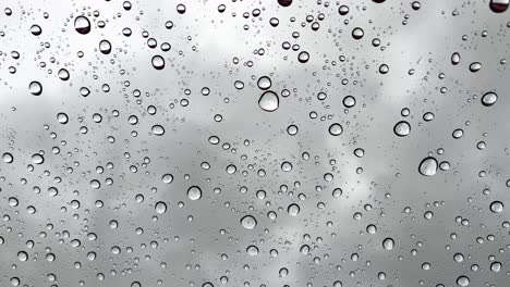 vertical wallpaper closeup real-time raindrops falling on the glass on a gray cold rainy day