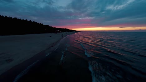 FPV-drone-flying-fast-over-the-waves-of-the-Baltic-Sea-in-Poland-with-blue-and-pink-colors-from-the-sunset