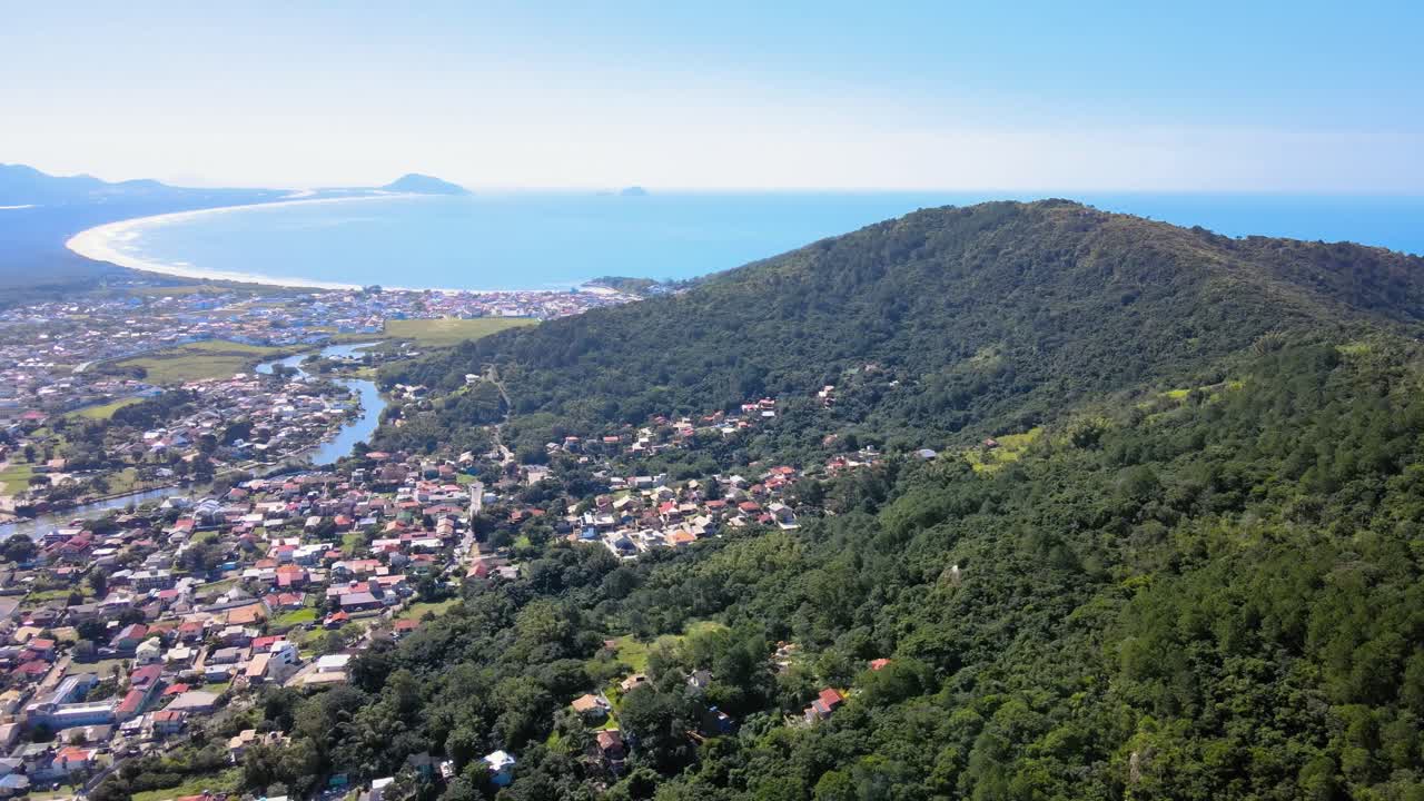 Aerial panoramic drone view of Barra da Lagoa, an urbanized neighborhood with a freshwater canal running through the city that flows into the sea, Florianópolis, Santa Catarina, Brazil