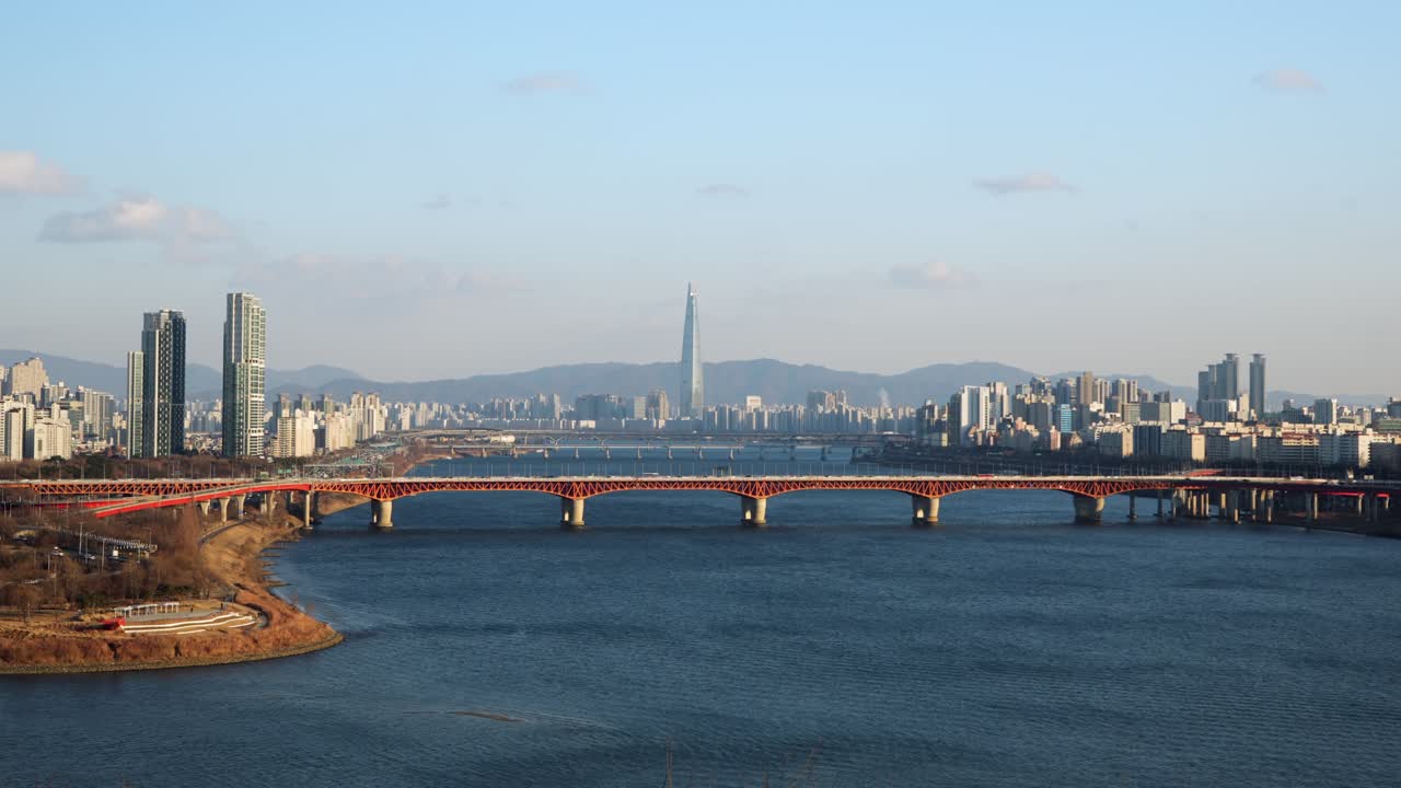 Time lapse invernale dello skyline di Seul che mostra il traffico che attraversa il ponte Seongsu sul fiume Han con la Lotte World Tower e nuvole bianche in rapido movimento nel cielo blu