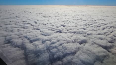 vista desde la ventana de un avión sobre nubes soleadas con cielo azul