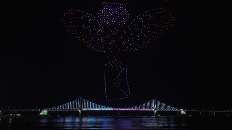 gwangalli beach drone light show above gwangan bridge in busan, south korea. glowing flying drones hive froming owl figure carrying letter