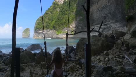 una chica balanceándose en una playa, nusa penida bali indonesia